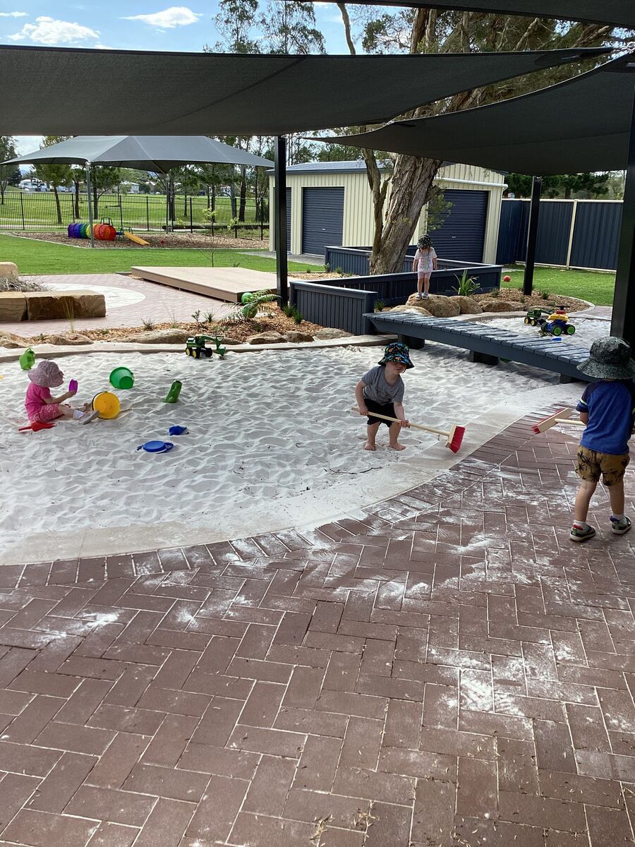 Children play in the sand area, scooping and building