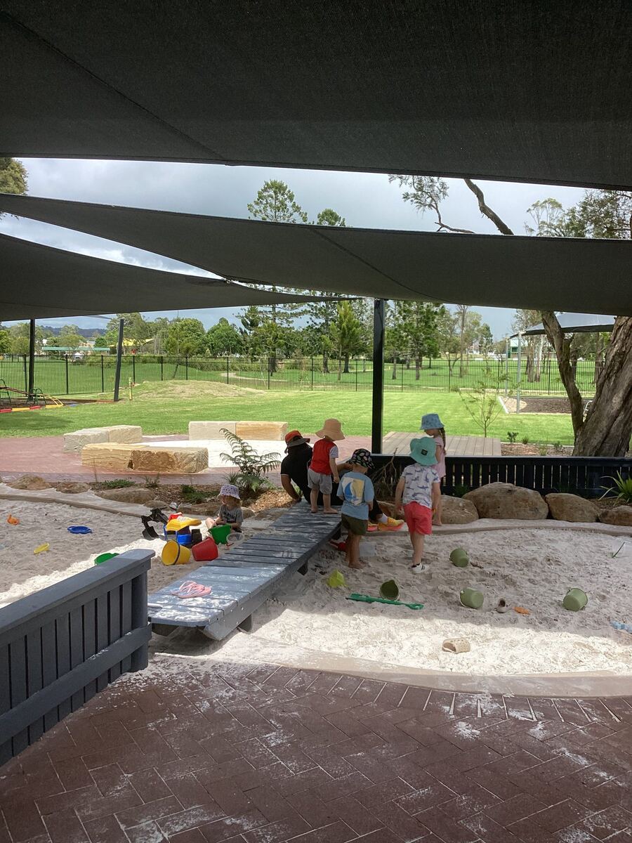 Children explore materials in the sandpit with educators